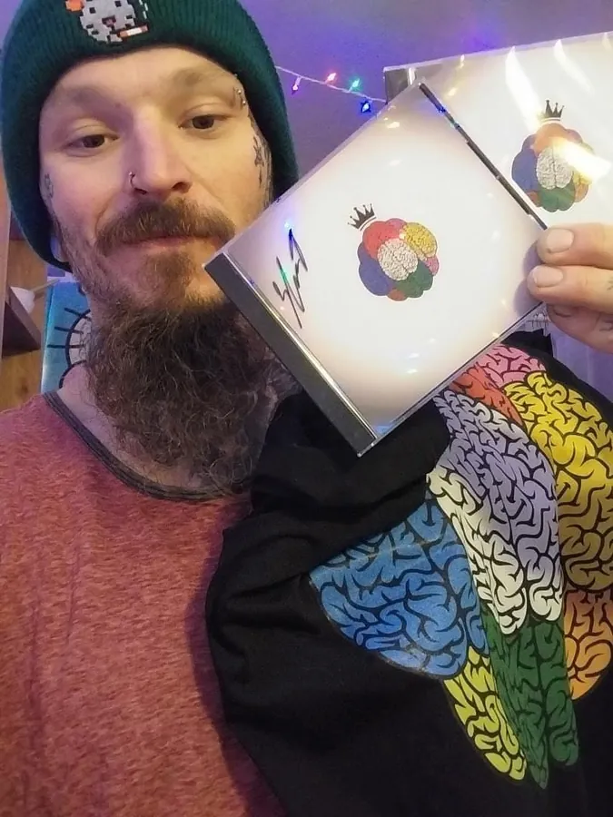 Fan in the brain tee holding a signed CD